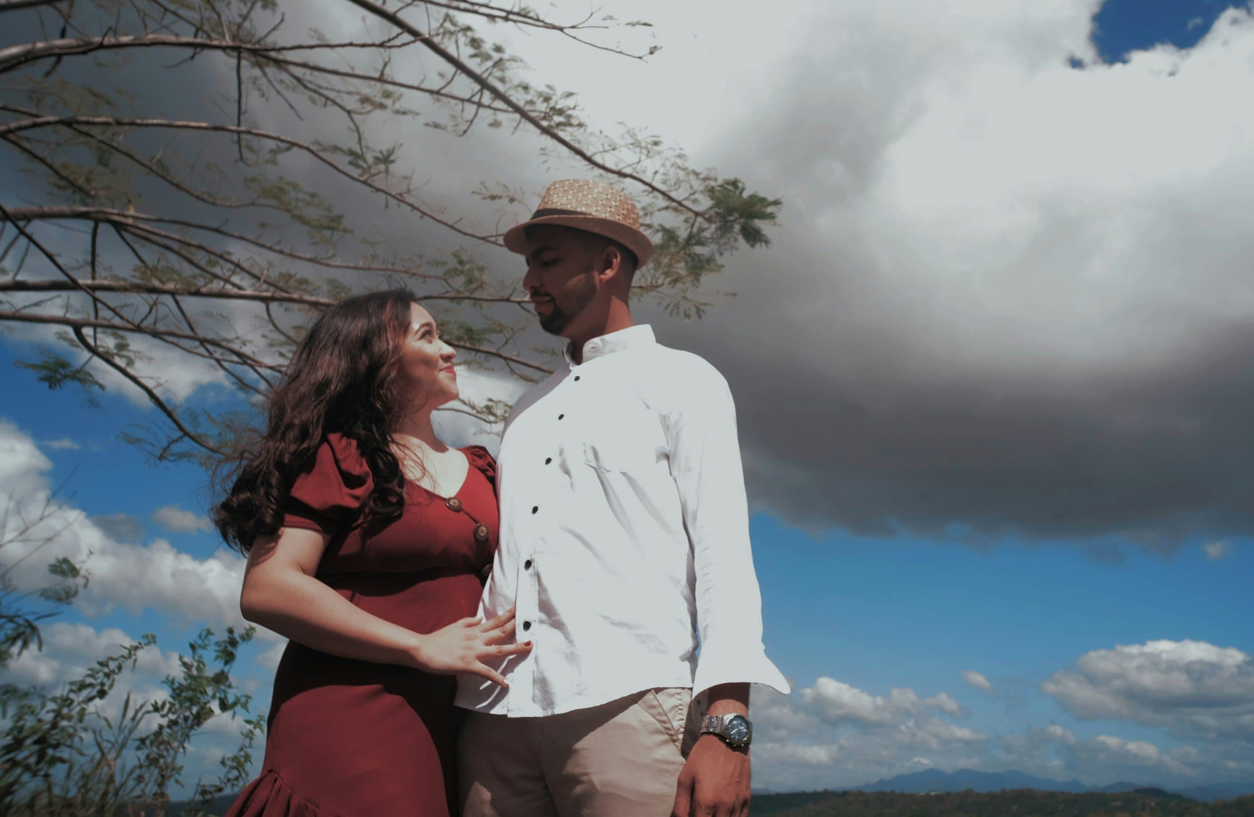 Couple stand together by a tree in nature