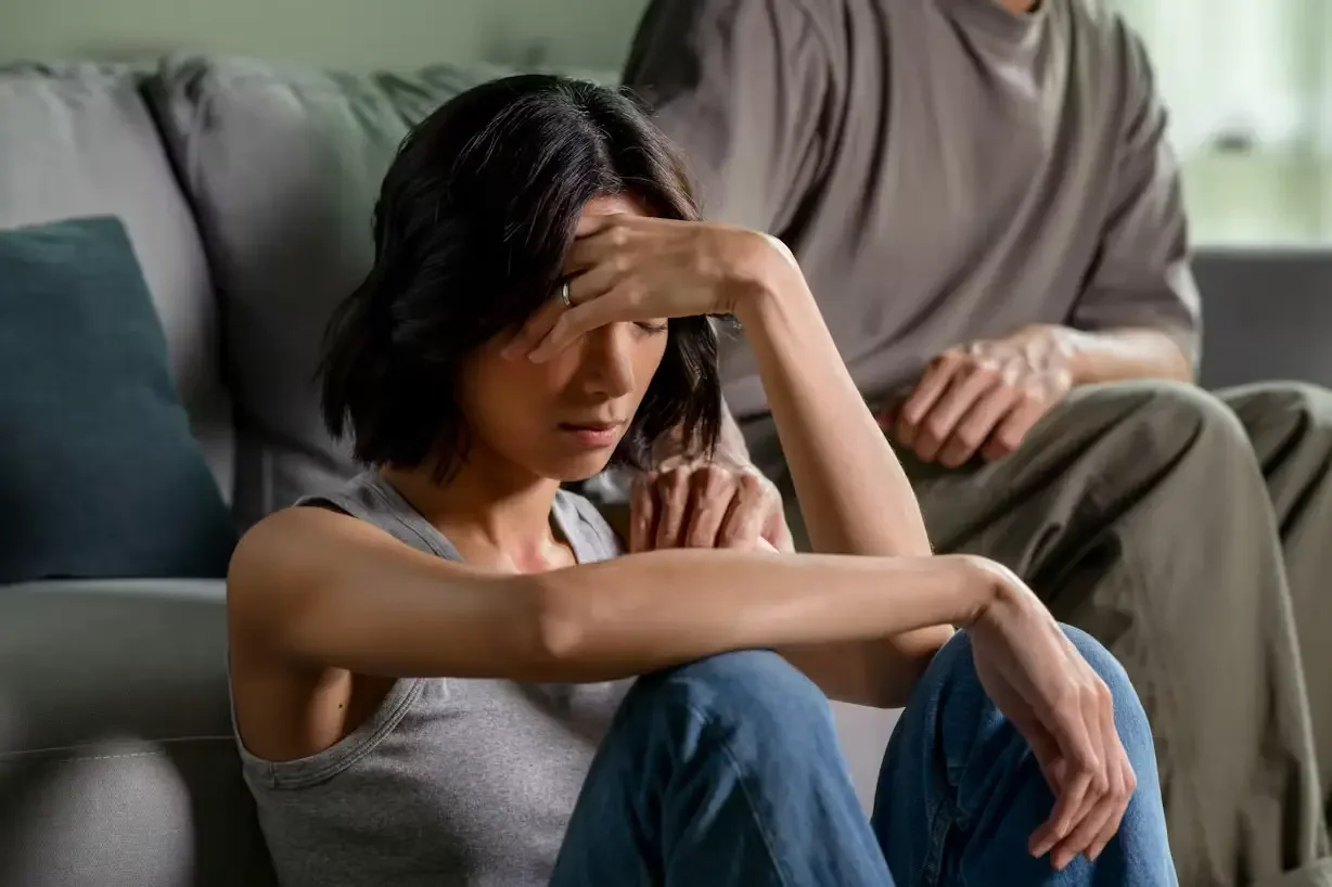 A woman with her hand to her head next to her partner holding her shoulder