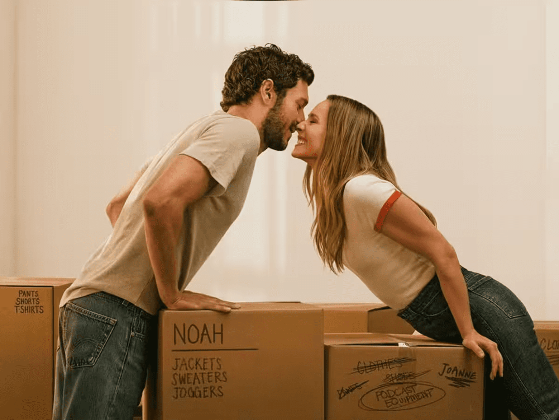 Kristen Bell and Adam Brody lean toward a kiss over moving boxes labelled Joanne and Noah
